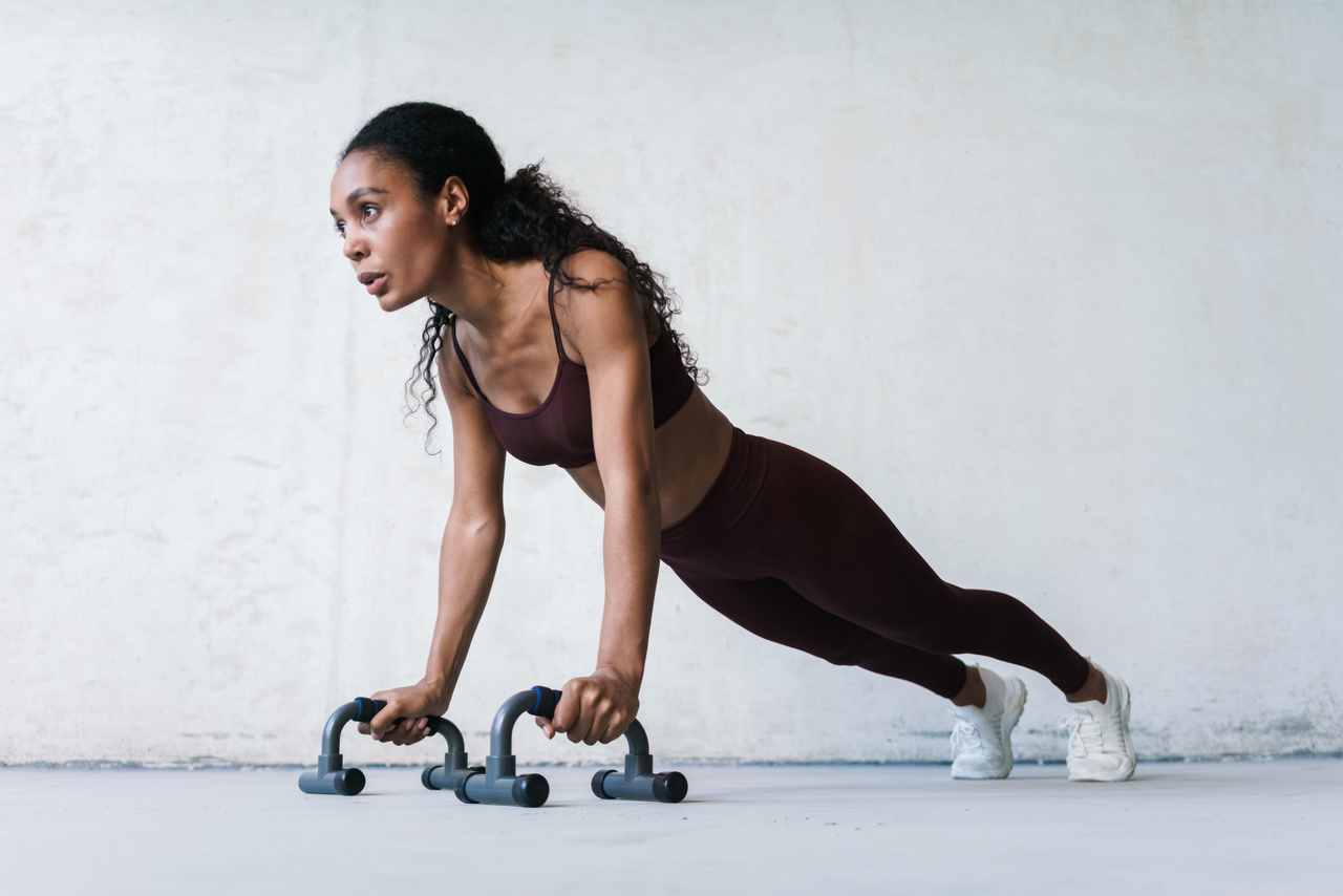mulher fazendo o exercício flexão de braços na academia